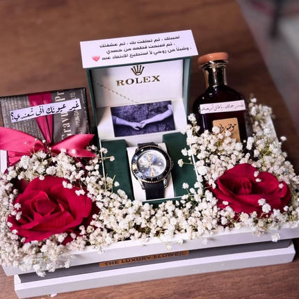 عرض علوي للبوكس يظهر ساعة Rolex فاخرة جداً في علبة بيضاء، وردة حمراء حقيقية معطرة، صور خاصة مع رسالة عربية رومانسية، وزهور جافة بيضاء معطرة براقة.