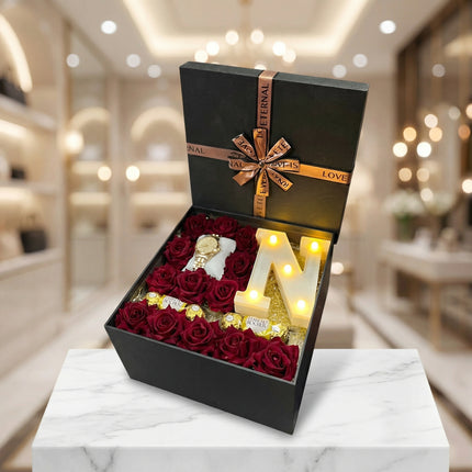 بوكس هدايا راقٍ من كنوز مصر يحتوي على حرف N مضيء وورود حمراء وعطر نسائي وساعة داخل تنسيق فاخر في أجواء رومانسية دافئة.